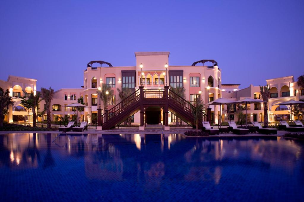 a large swimming pool in front of a building at Shangri-La Hotel Apartments Qaryat Al Beri in Abu Dhabi