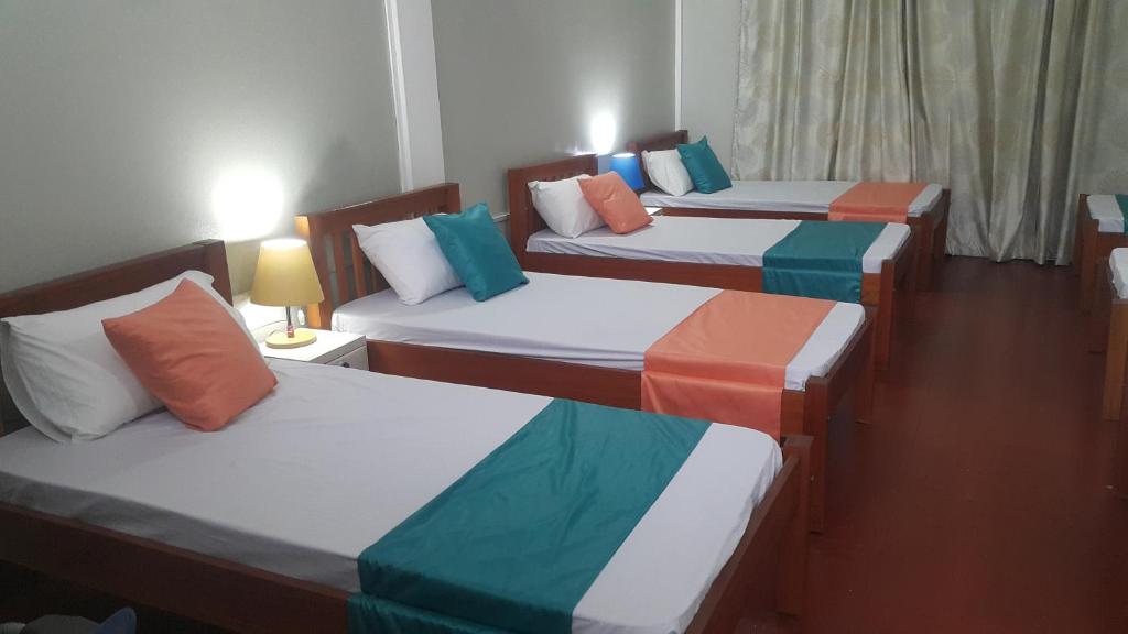 a room with three beds with different colored sheets at CDH Backpackers in Mombasa