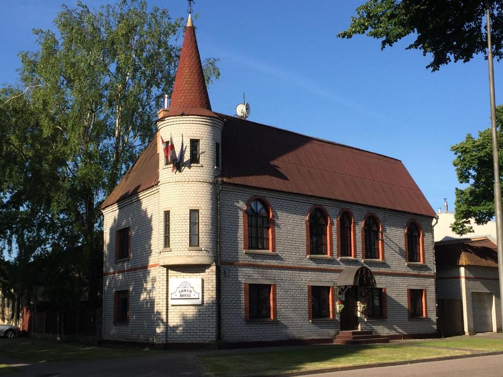 ein altes Gebäude mit einem Turm darüber in der Unterkunft Tower Hotel in Ventspils