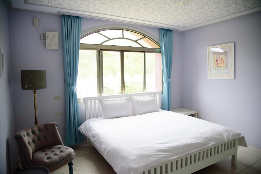 a bedroom with a bed and a window and a chair at Green 58 B&amp;B in Hengchun South Gate