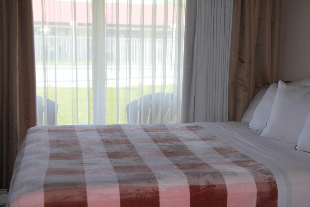 a bedroom with a bed with a plaid blanket on it at Hotel Motel Bonsoir in Granby