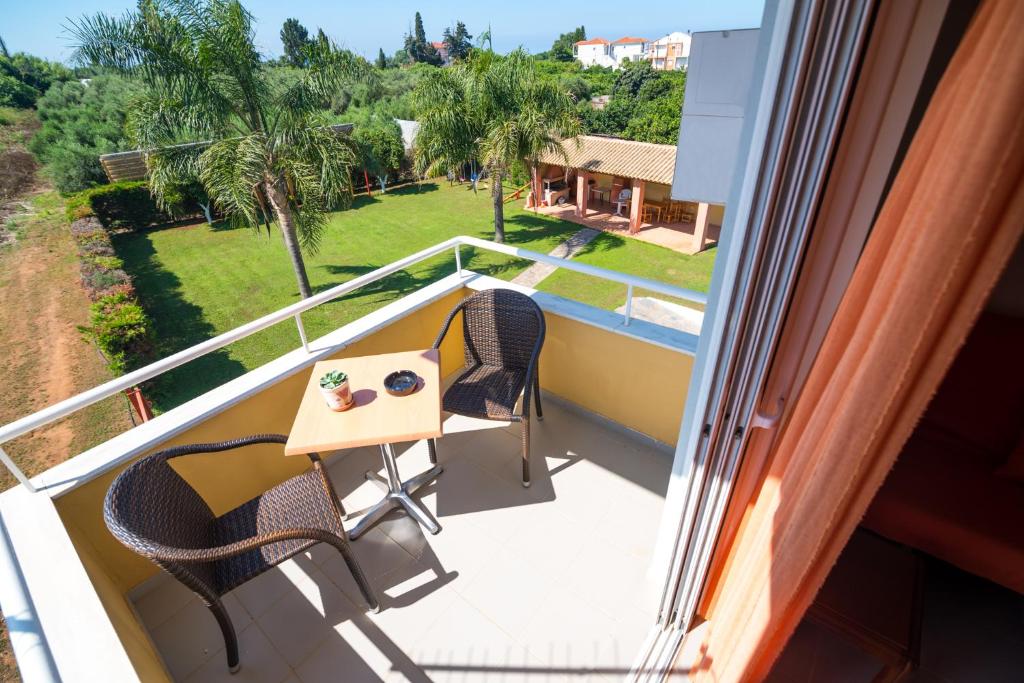 a balcony with a table and chairs and a view of a yard at Voula Apartments in Mytikas