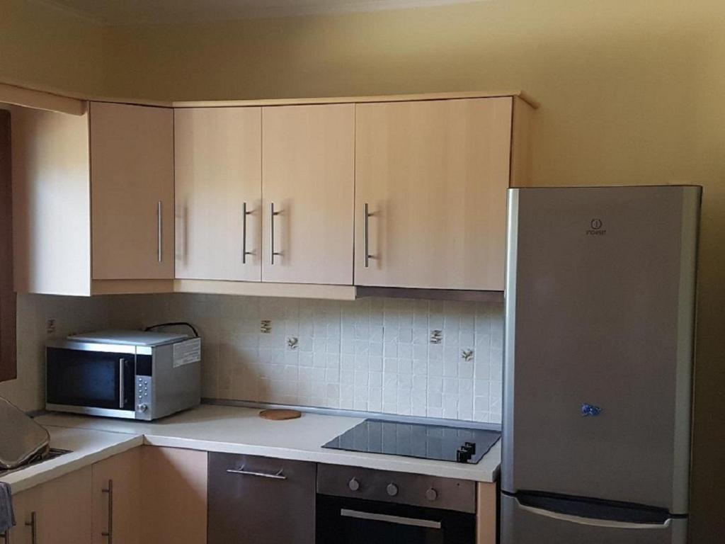 a kitchen with white cabinets and a stainless steel refrigerator at Studio Foris in Sivota