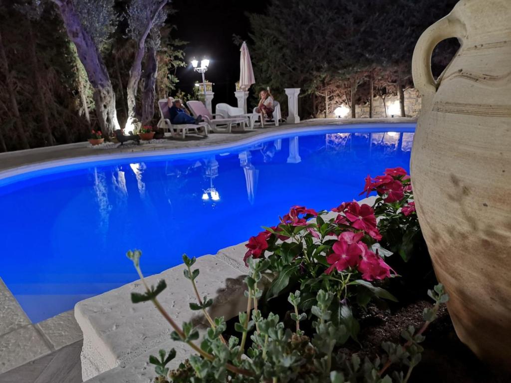 a pool at night with people sitting in chairs and flowers at B&B Villa del Sole Relais in Agrigento