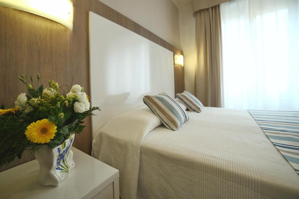 Cette chambre d'hôtel comprend un lit avec un vase de fleurs. dans l'établissement Hotel Villa Rosa, à Sestri Levante
