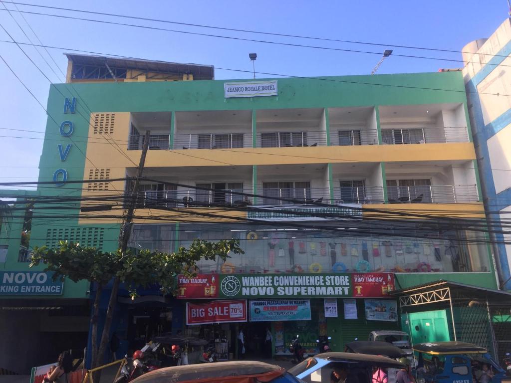 ein Gebäude an einer belebten Straße mit Autos in der Unterkunft Jeamco Royal Hotel-Palawan in Puerto Princesa