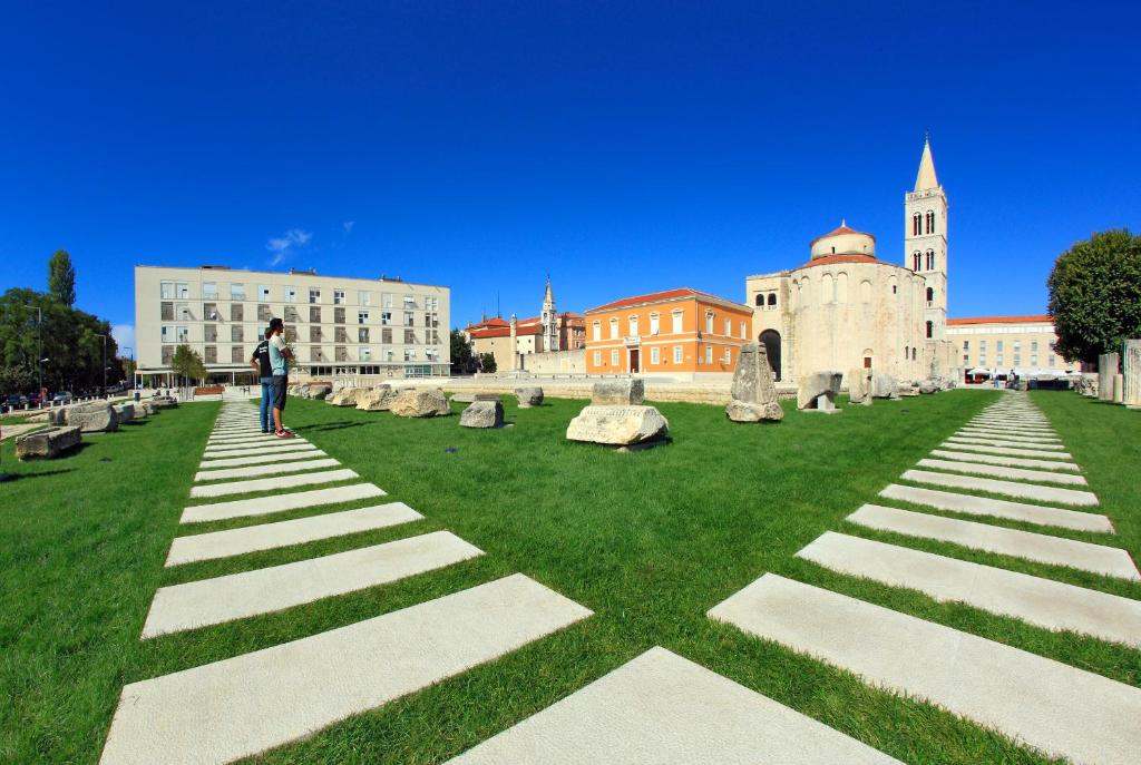 une personne debout sur l'herbe devant un bâtiment dans l'établissement Apartments Maruna Self check-in, à Zadar