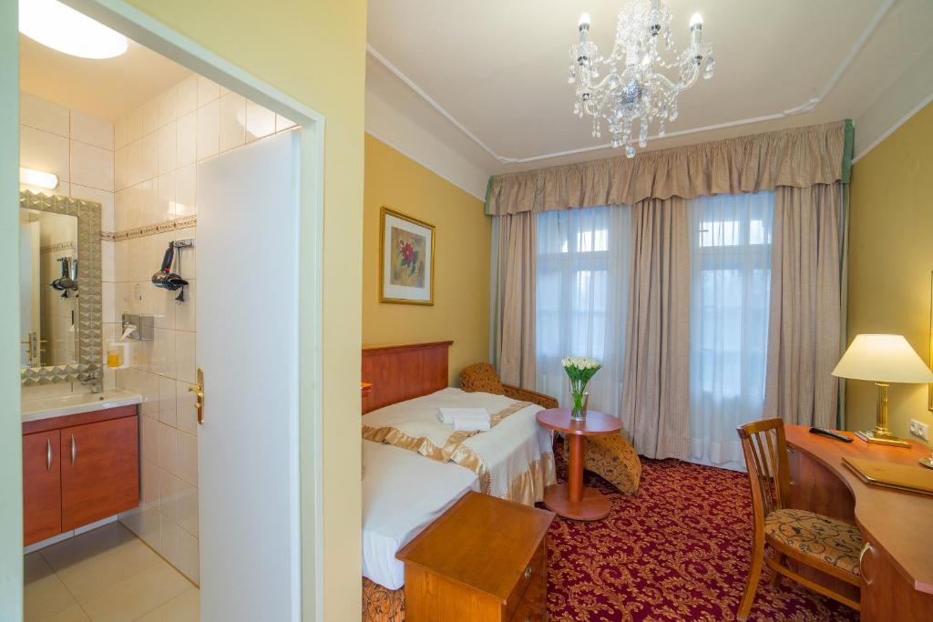 a bedroom with a bed and a desk and a bathroom at Spa Resort PAWLIK-AQUAFORUM in Františkovy Lázně