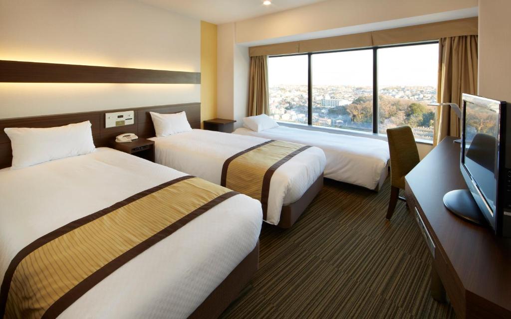 a hotel room with two beds and a flat screen tv at Shin Yokohama Prince Hotel in Yokohama