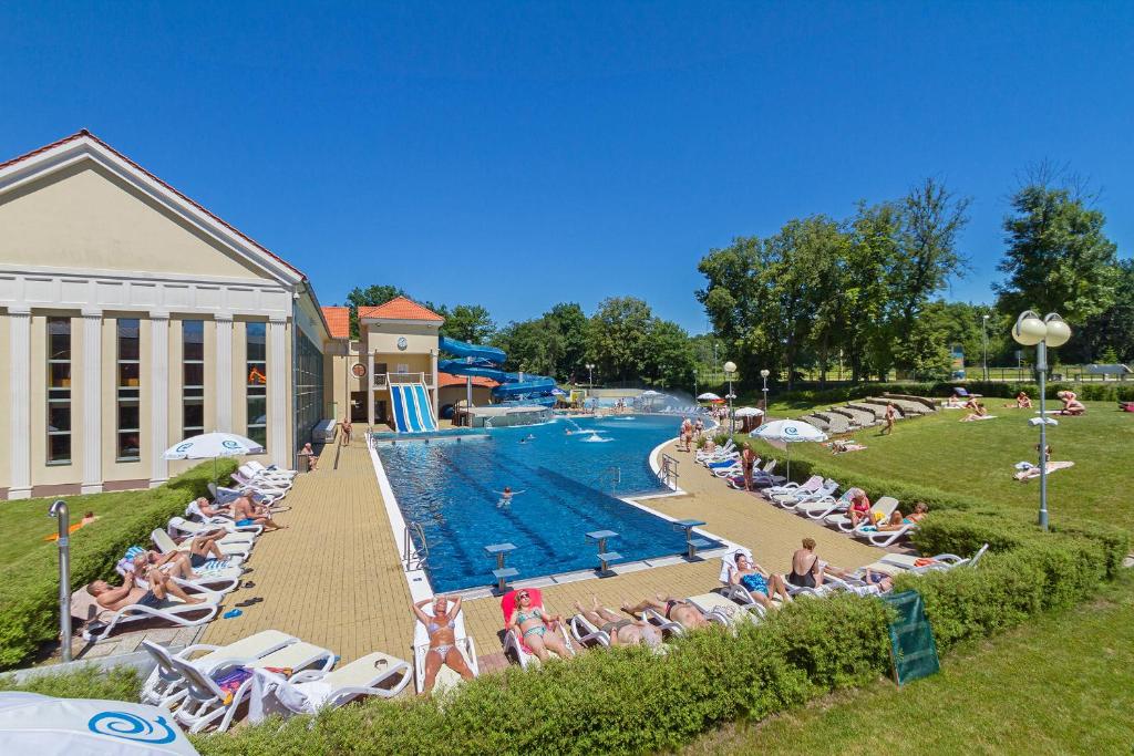 a large swimming pool with people sitting in chairs at a resort at Spa Resort PAWLIK-AQUAFORUM in Františkovy Lázně