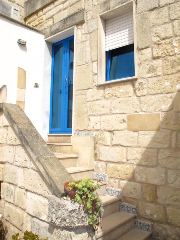 una casa de piedra con una puerta azul y escaleras en Otranto Vacanza Facile - Via San Francesco Da Paola, en Otranto