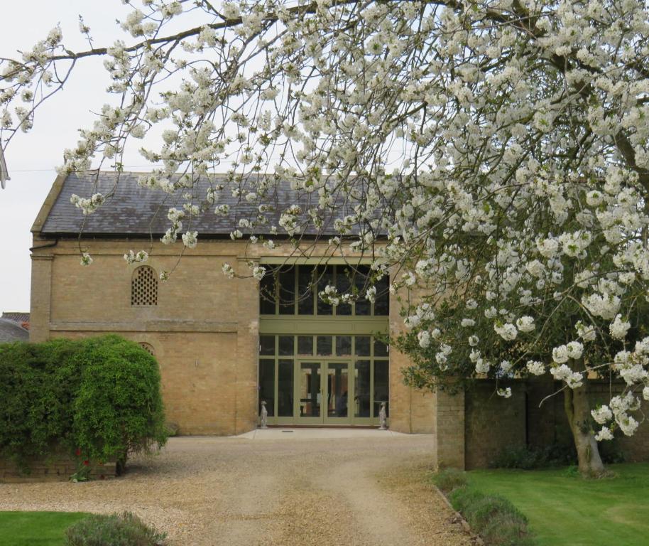 un edificio con un árbol florido delante de él en Owl Barn en Kings Lynn