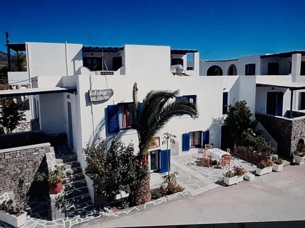 a white building with a palm tree in front of it at Holidays in Paros in Aliki