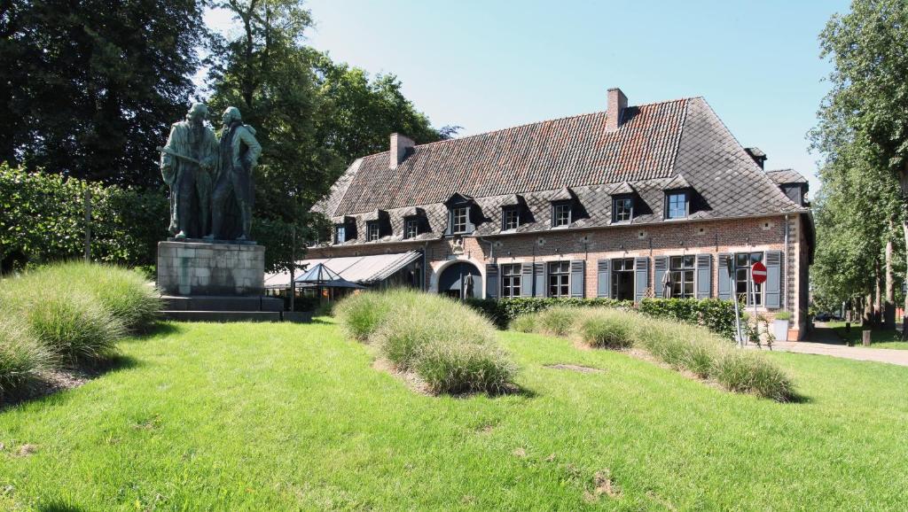 une statue de deux personnes devant un bâtiment dans l'établissement Hotel The Lodge Heverlee, à Louvain