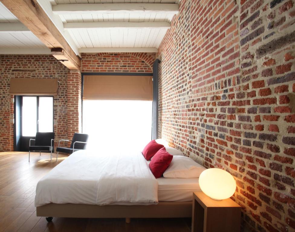 a brick walled bedroom with a bed and a window at Hotel The Lodge Heverlee in Leuven
