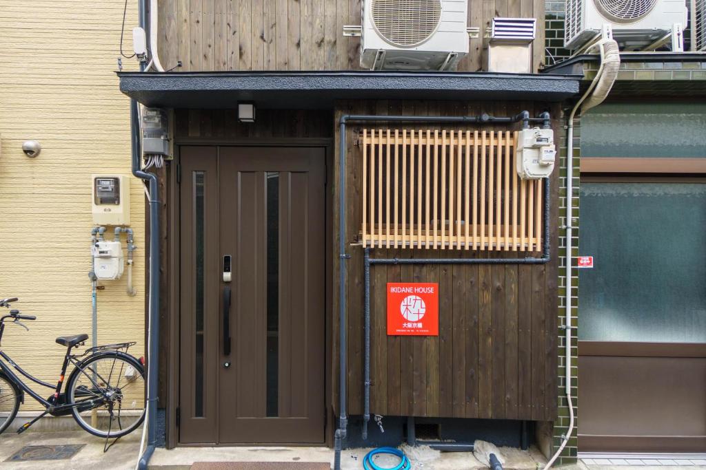 un edificio con una puerta y una bicicleta estacionada al lado en Ikidane House Osaka Kyobashi en Osaka