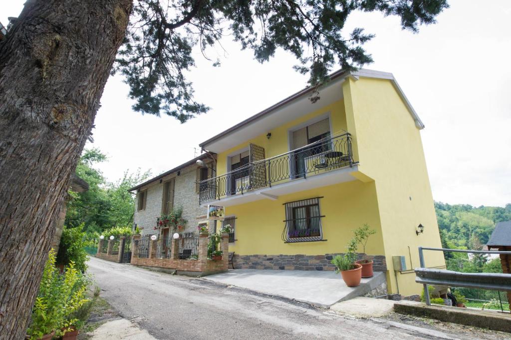 ein gelbes Haus mit einem Baum davor in der Unterkunft B&B Villa Filetta in Marsia