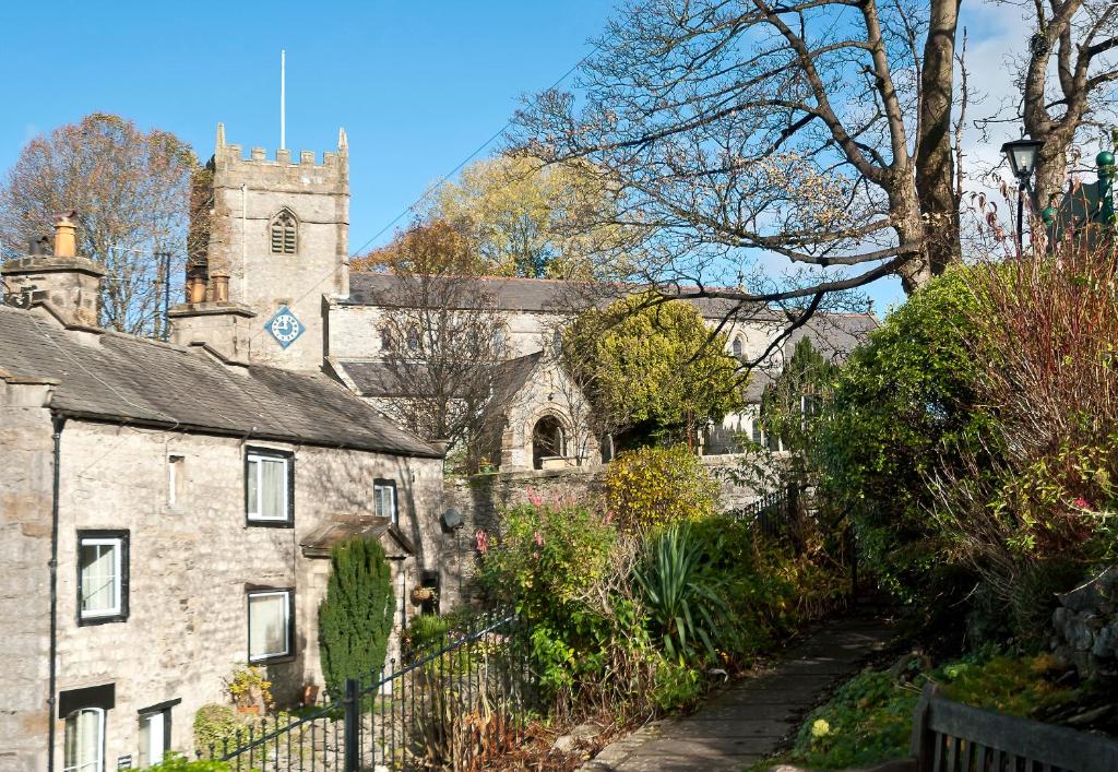 an old stone building with a church in the background at Our Holiday House Yorkshire, Ingleton - children and doggy friendly in Ingleton 