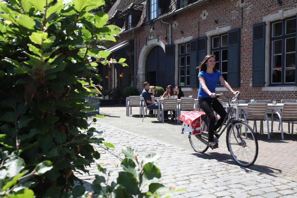 a woman riding a bike down a street at Hotel The Lodge Heverlee in Leuven