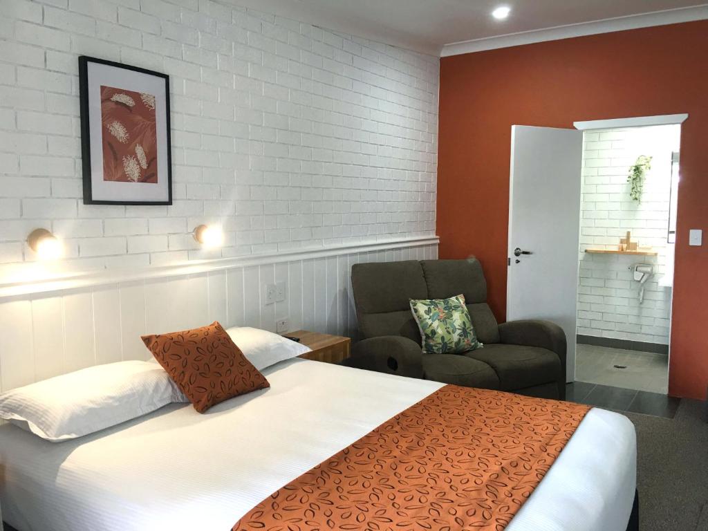 Habitación de hotel con cama y silla en Gin Gin Village Motor Inn Motel QLD en Gin Gin