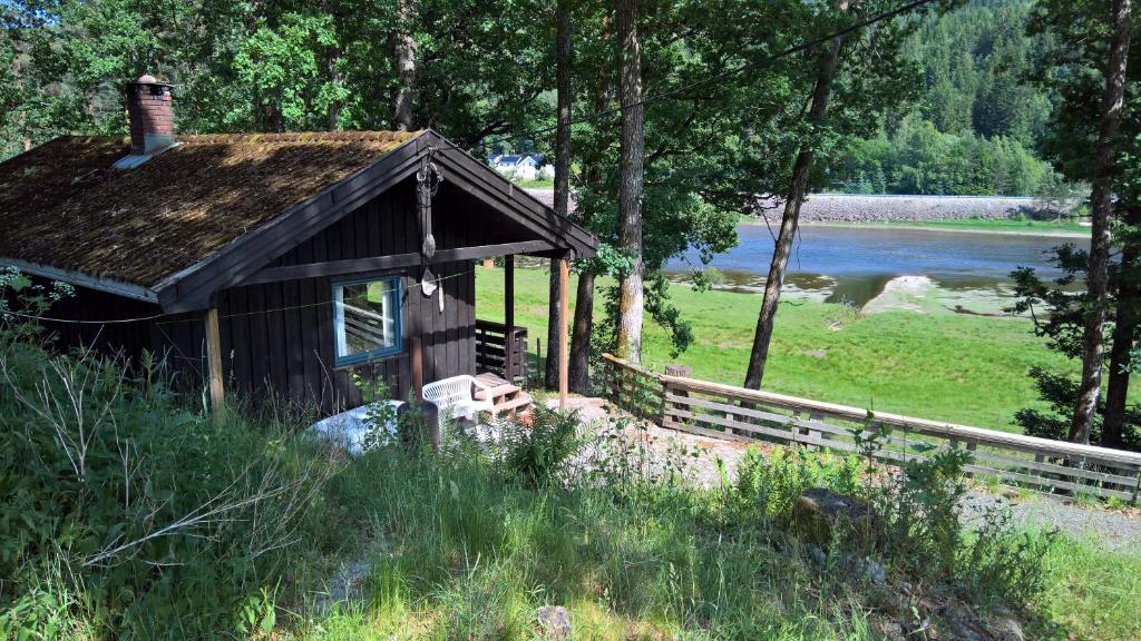 an old cabin in the woods next to a river at Strandheim Two-Bedroom Cottage in Birkeland