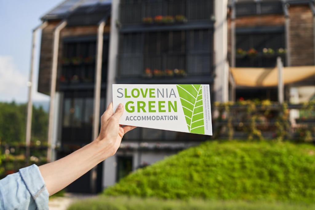 a person holding up a sign that reads slowermite green approximation at eco boutique hotel AMS Beagle in Bled