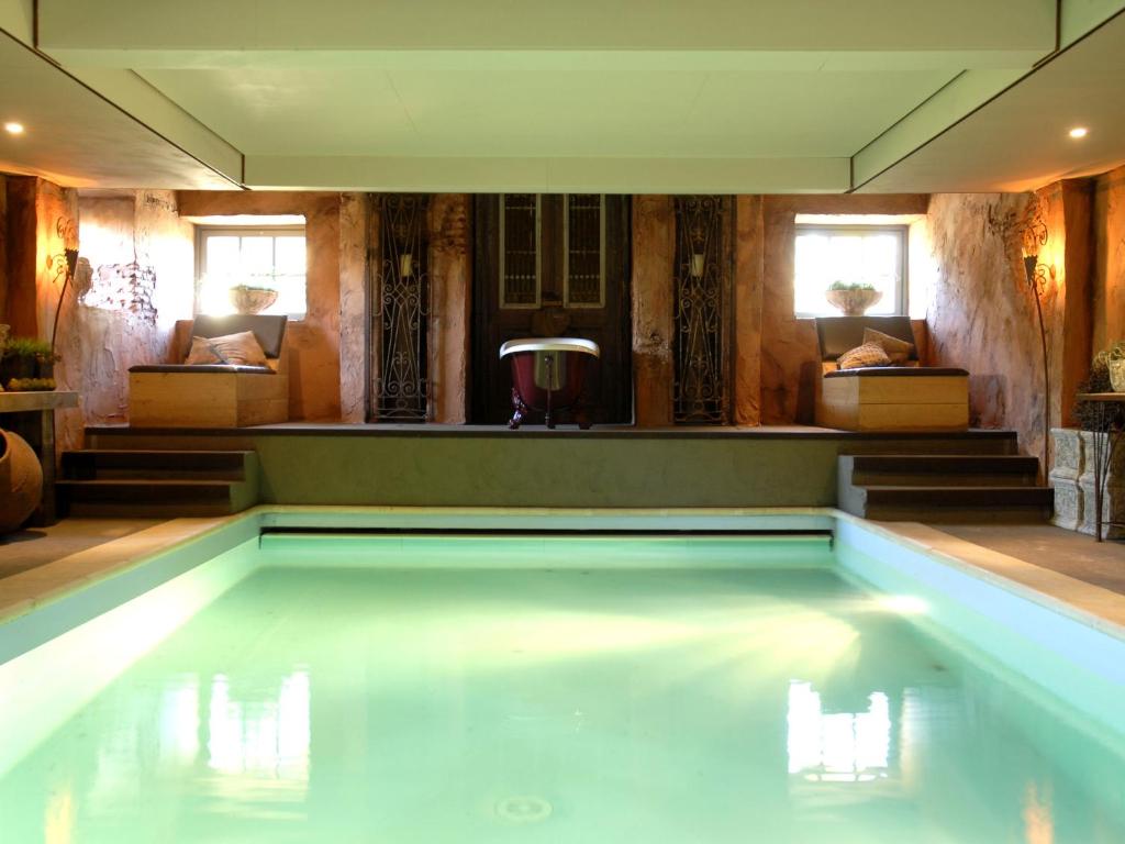 a swimming pool in a room with chairs and a couch at Grand Holiday Home in Alphen with Sauna in Alphen