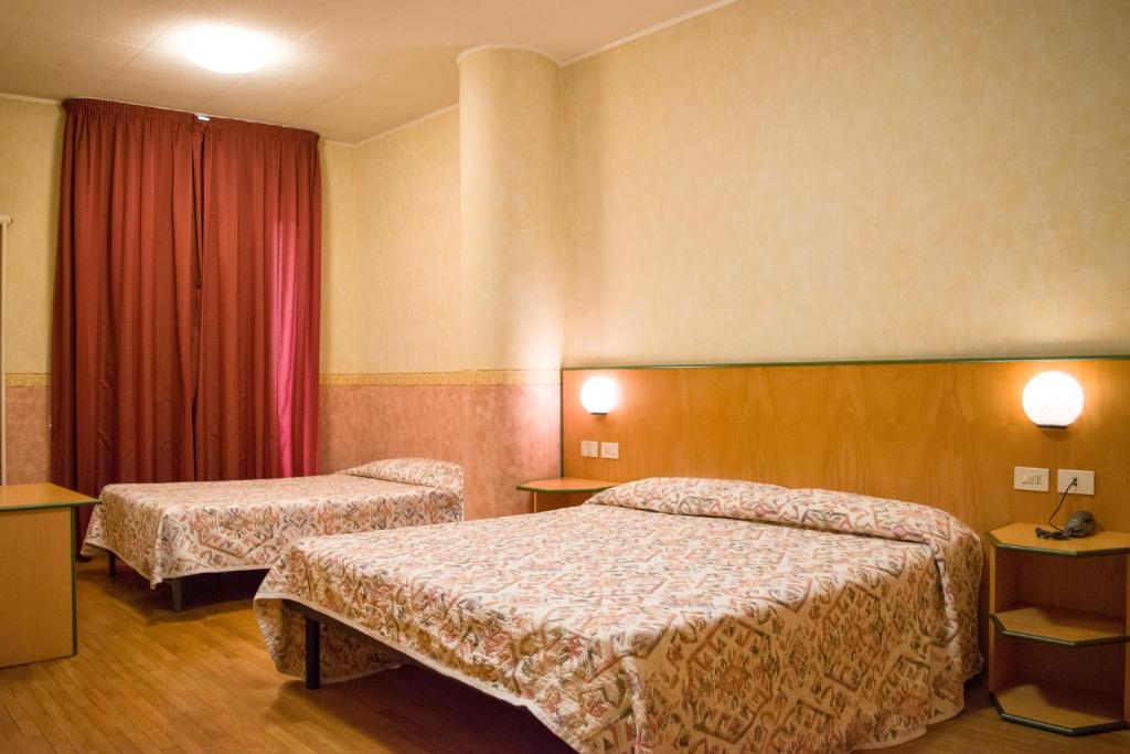 a hotel room with two beds and red curtains at Hotel Baffo Rosso in Alba Adriatica