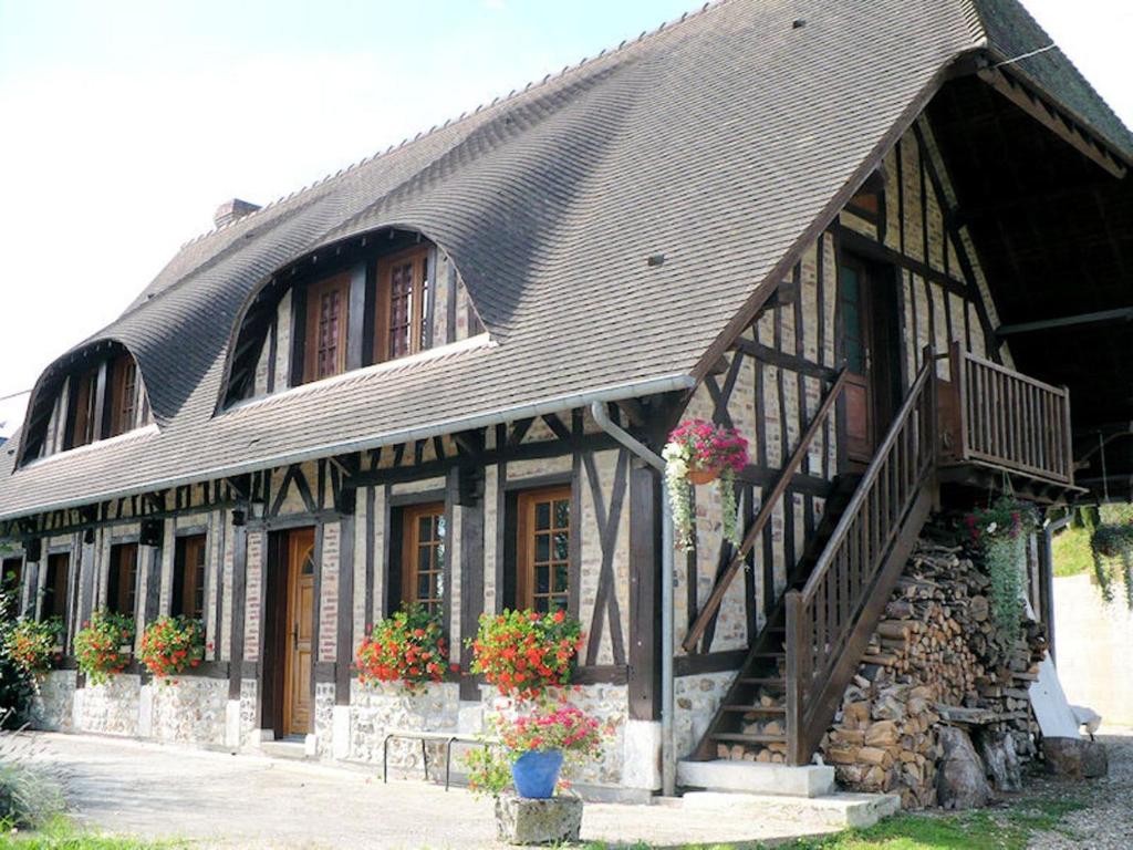 una casa con techo de gambrel con flores en las ventanas en En Bord de Seine, en Duclair