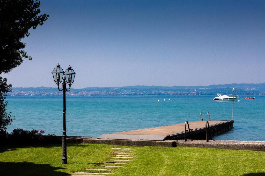 um poste de luz na grama ao lado da água em Sirmio Apartments - Primavera Stay em Sirmione