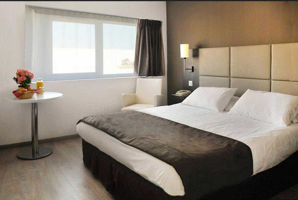 a hotel room with a large bed and a window at Séjours & Affaires Courbevoie Grande Arche in Courbevoie