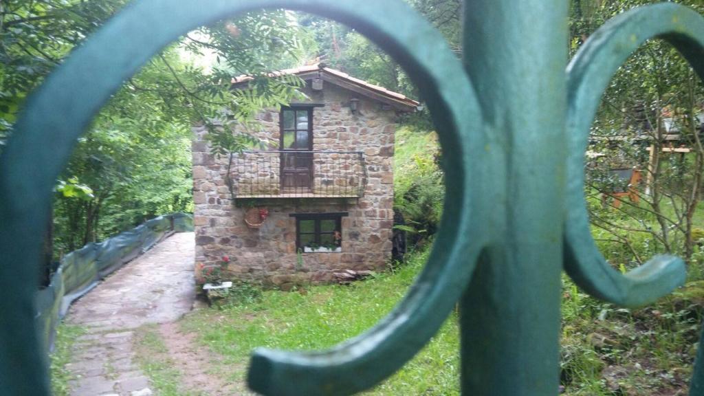 uma casa de pedra é vista através de uma cerca de metal em la casuca del bosque em Liérganes