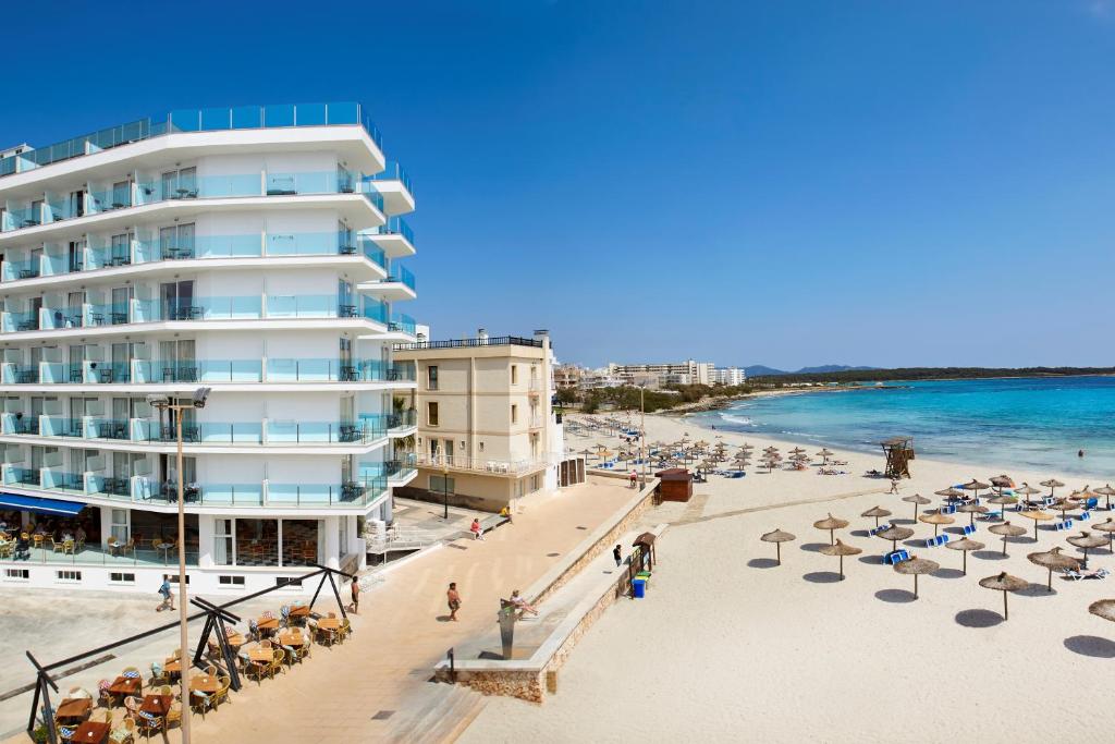 een uitzicht op een strand met een hotel en de oceaan bij Universal Hotel Perla in S'Illot