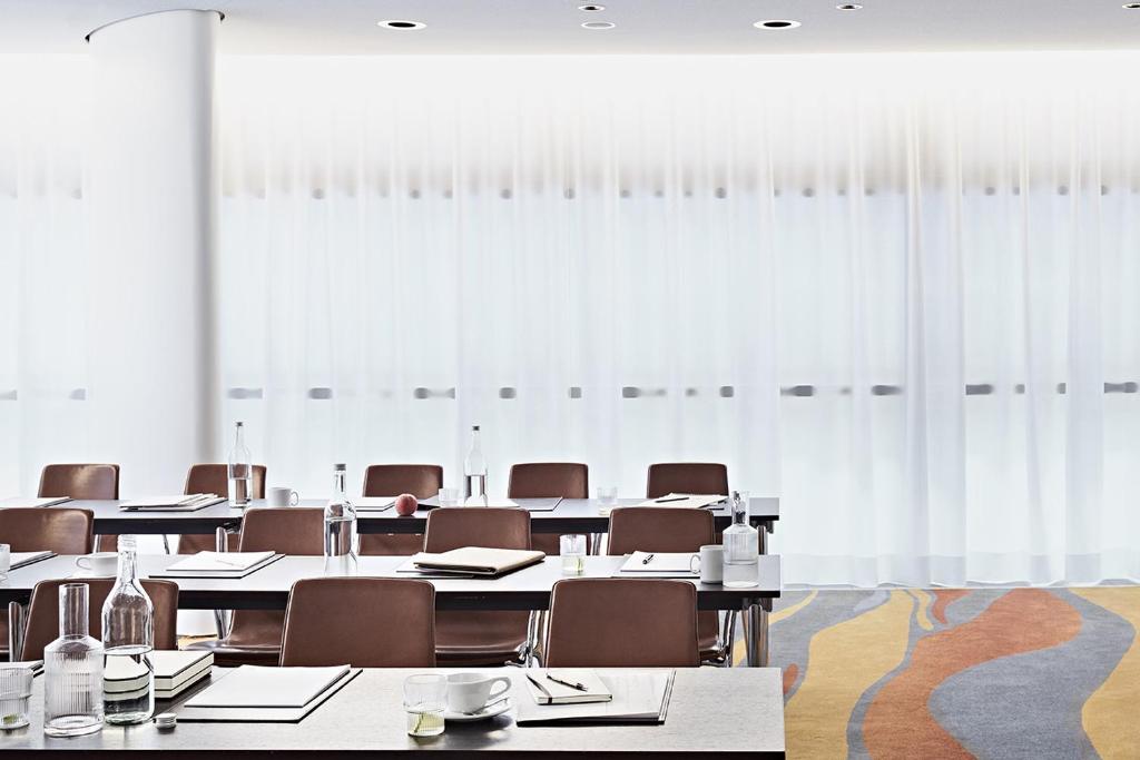 a room with tables and chairs and white curtains at SIDE, Hamburg, a Member of Design Hotels in Hamburg