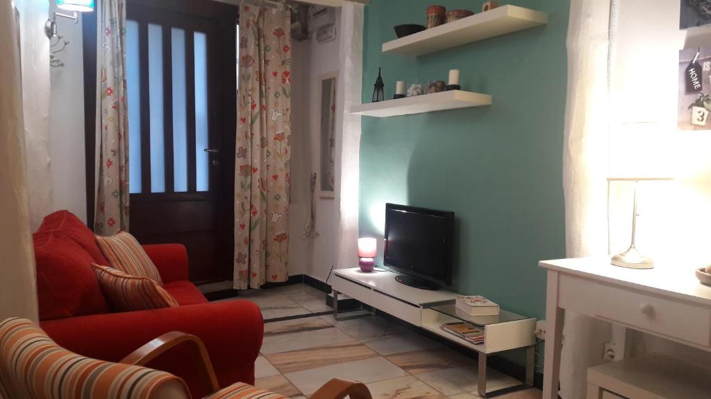 La casita del jerte في كابيزويلا ديل فالي: غرفة معيشة مع تلفزيون وأريكة حمراء