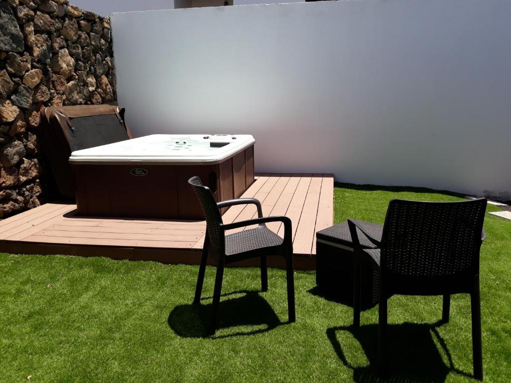 two chairs and a hot tub on a deck with grass at Loft La Tahonilla in Tías