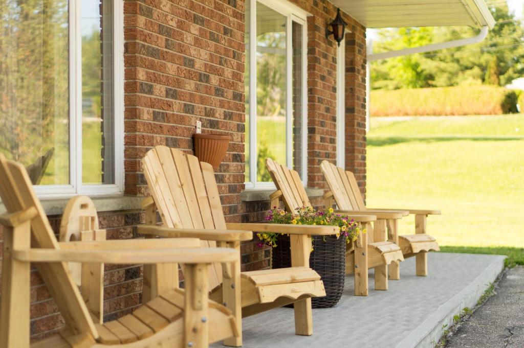 a row of wooden chairs sitting on a porch at Wayside Motel Manitoulin in Manitowaning