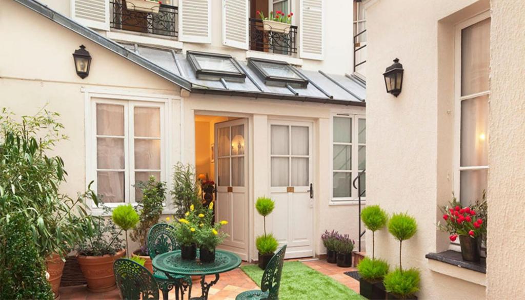 um pátio com uma mesa e cadeiras em frente a uma casa em Castex Hotel em Paris