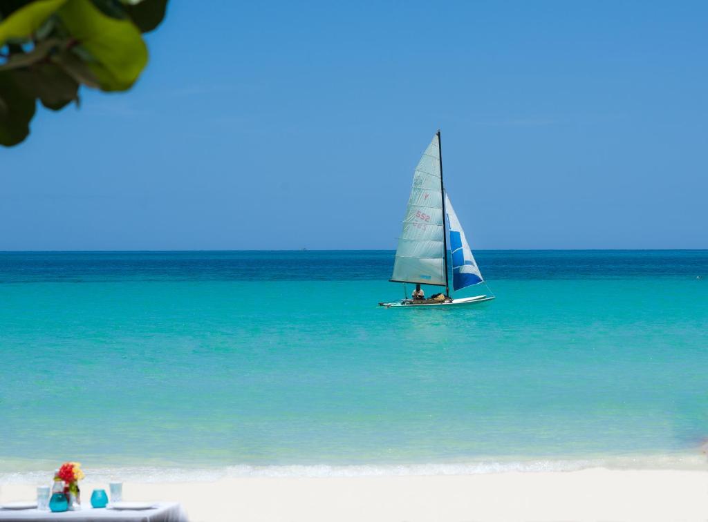 un velero en el agua en una playa en Secret Cabins at Firefly Beach Cottage, en Negril