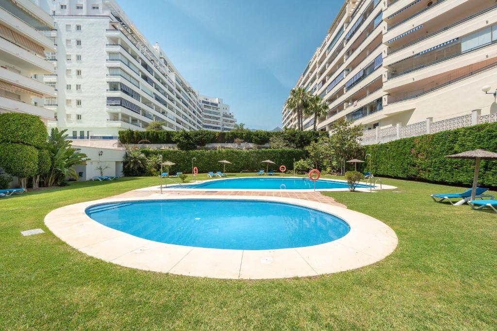 una gran piscina en medio de un césped con edificios en Apartamento Azul, en Marbella