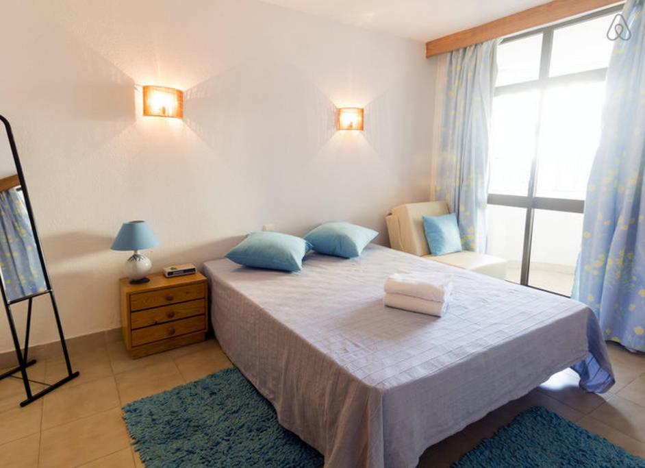 Roja- PéにあるApartamento T1 a 250 metros da Praia - Albufeiraのベッドルーム1室(青い枕のベッド1台、窓付)