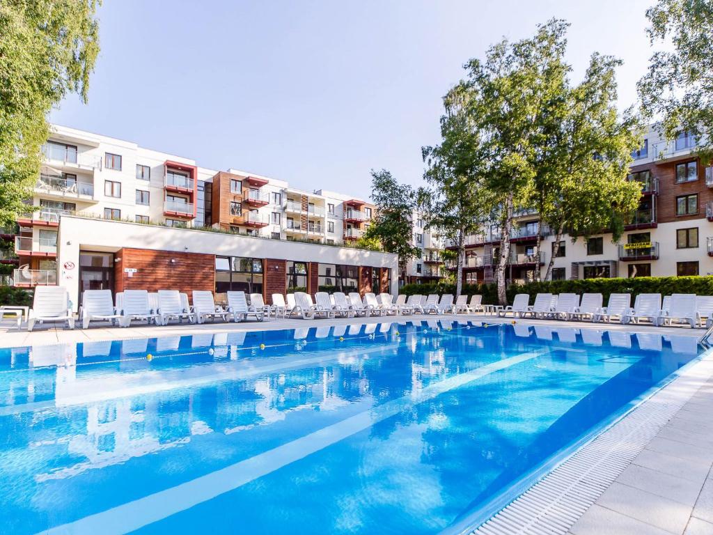 una gran piscina con tumbonas y edificios en Apartament pomarańczowy z basenem,sauną-blisko morza. en Kołobrzeg