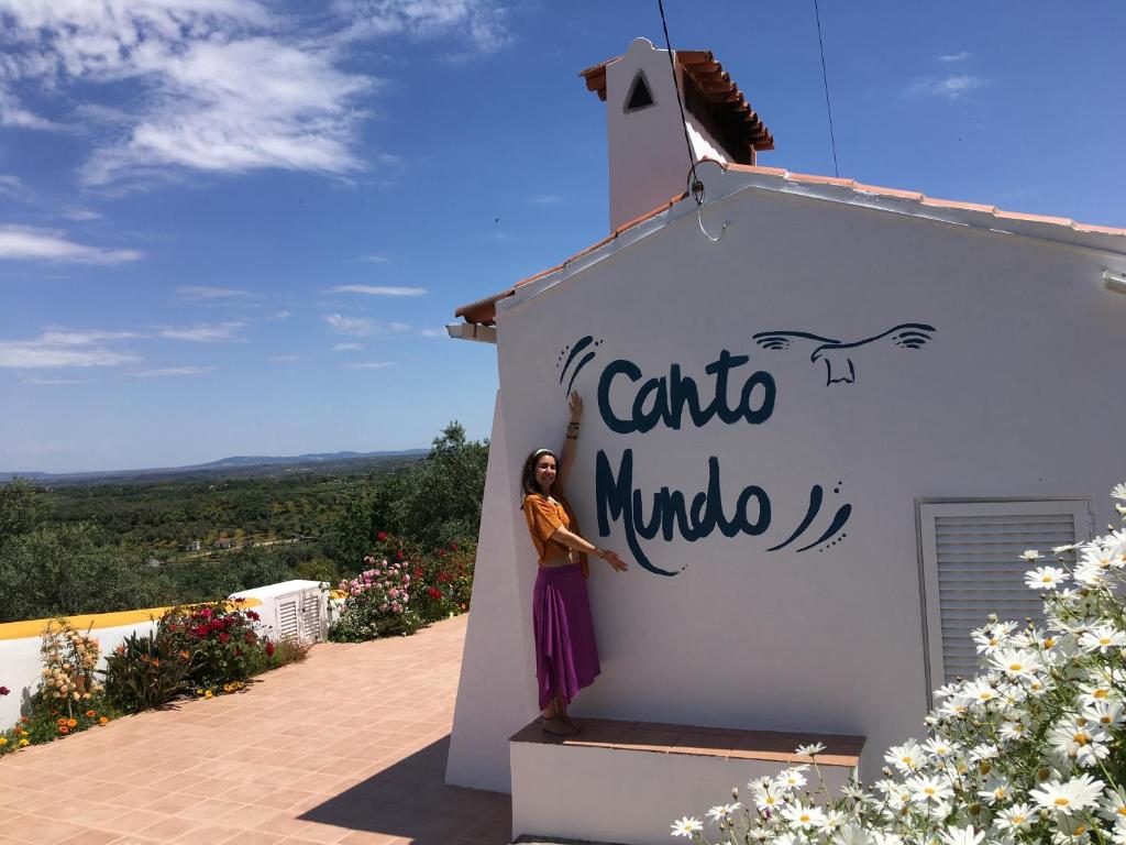 een vrouw die aan de zijkant van een gebouw staat bij Canto Mundo in Castelo de Vide