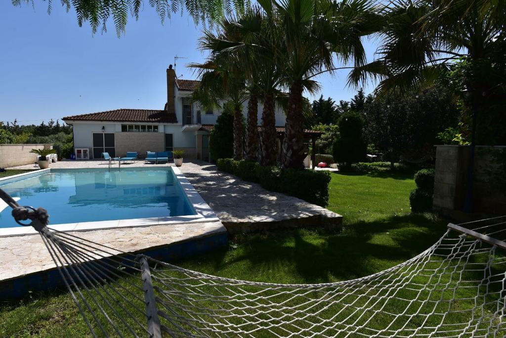 una hamaca frente a una casa con piscina en AgrIGINO Villa Riccardi, en Matera