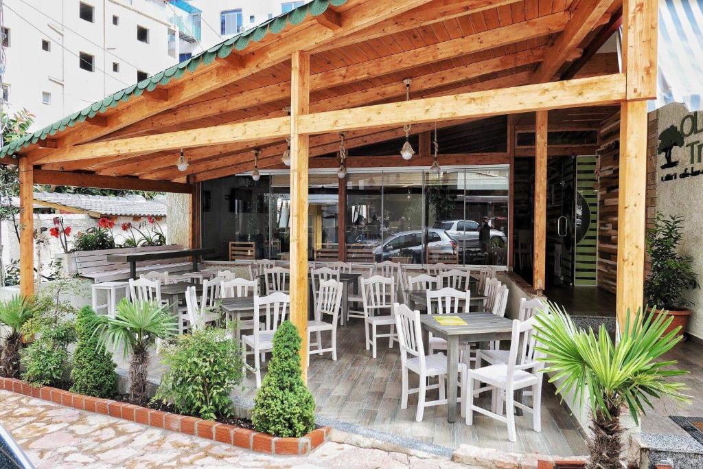 a patio with white chairs and tables and a building at Olive Tree in Sarandë