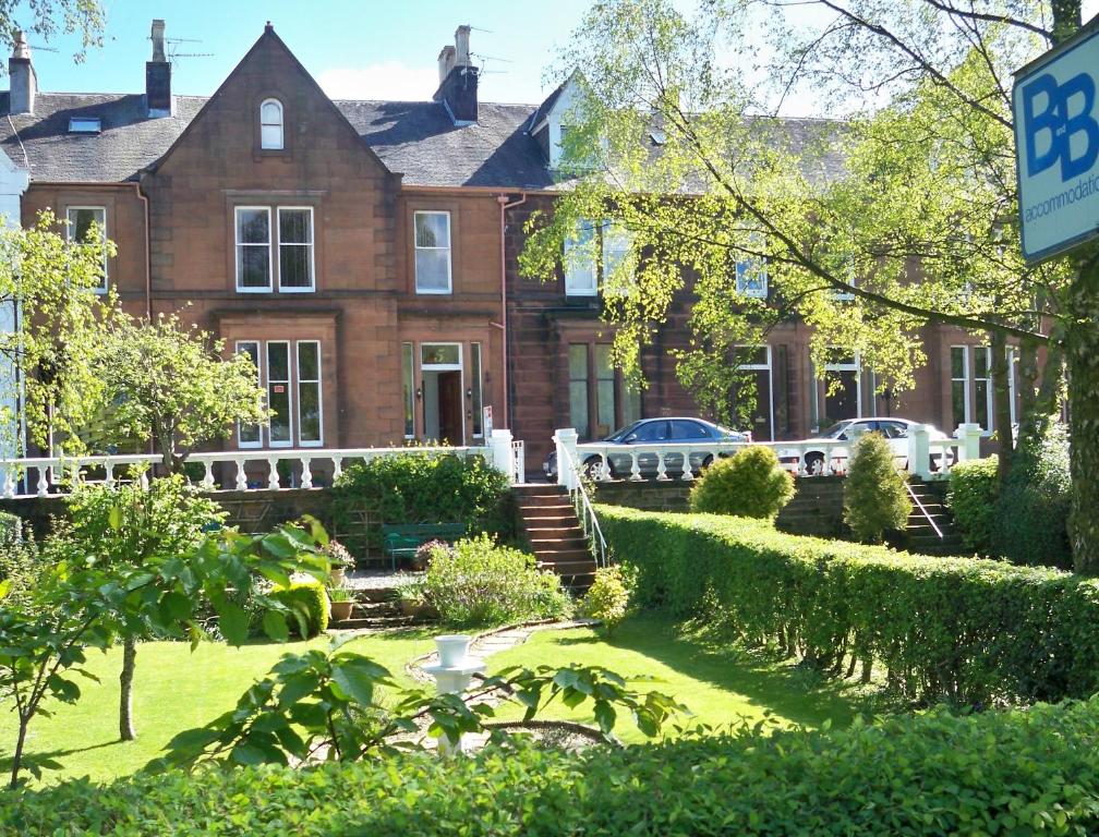 una gran casa de ladrillo con coches estacionados frente a ella en Glenaldor House B&B en Dumfries