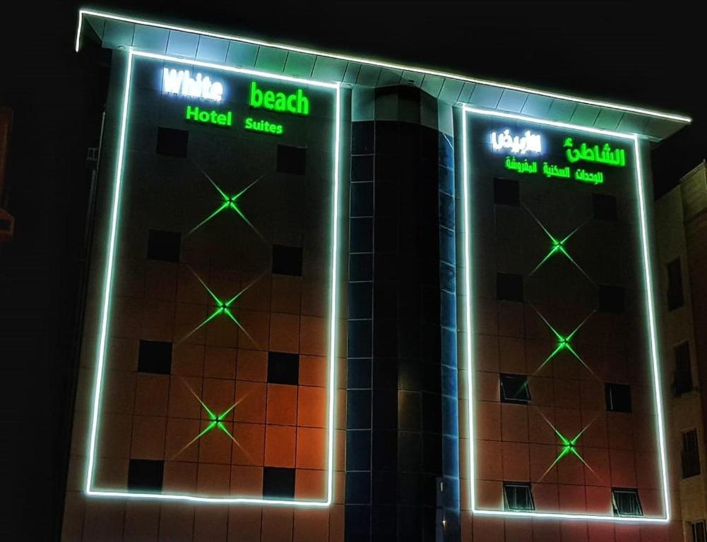 a building with neon signs on the side of it at White Beach Hotel Suites in Rabigh