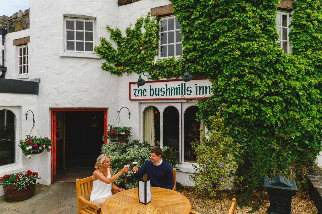 a man and woman sitting at a table in front of a building at Bushmills Inn Hotel & Restaurant in Bushmills