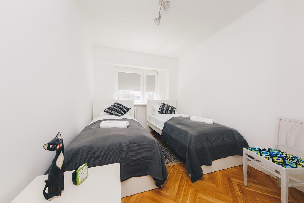 ワルシャワにあるShortStayPoland Aleja Solidarnosci (B61)の白い壁とウッドフロアの客室で、ベッド2台が備わります。