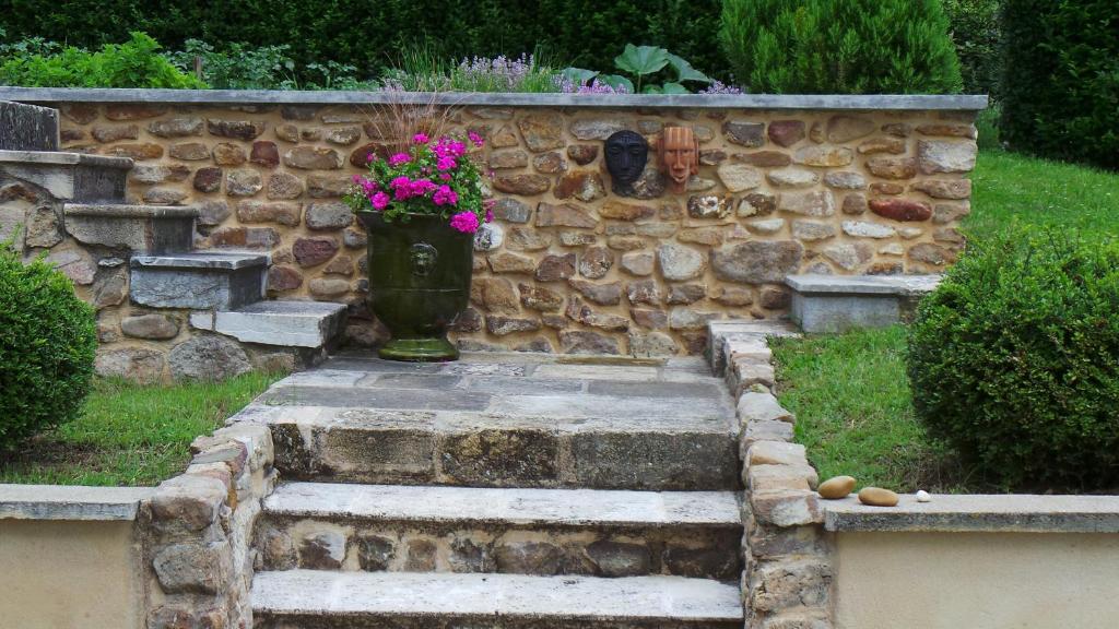 un vase avec des fleurs assis au-dessus d'un mur en pierre dans l'établissement Le balcon du fêtre (Maria & Jean Louis Chapuy), à Chiroubles